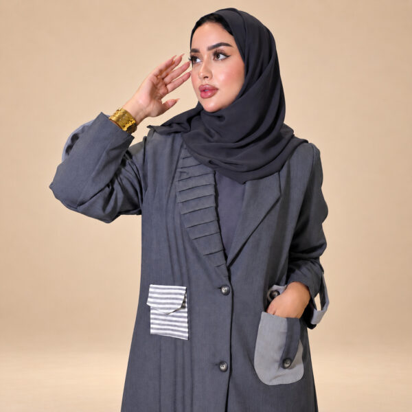 موديل ترتدي عباية أوربان مازيراتي الرمادية في إطلالة أمامية مائلة تُظهر الياقة والجيوب | Model wearing the grey Urban Maserati Abaya in a three-quarter front view showing the lapel and pockets